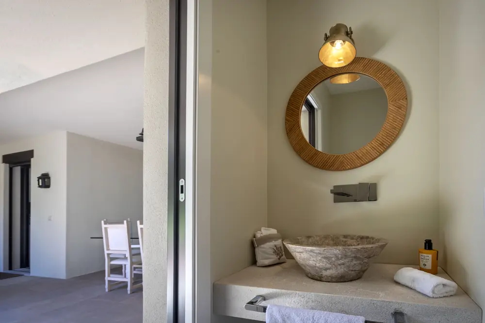 Basin carved from stone under a round rattan mirror