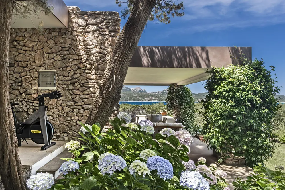 Outdoor fitness corner between hydrangeas and a stone wall, overlooking the gulf